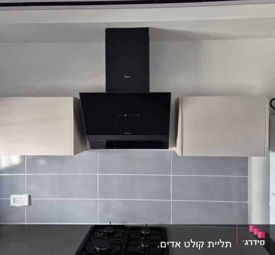 קולט אדים שחור מותקן במטבח מעל כיריים גז